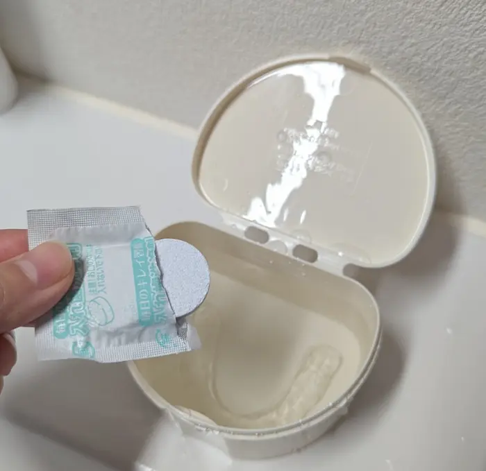 入れ歯洗浄ケースにマウスピースと水を入れたところに、洗浄剤を投入