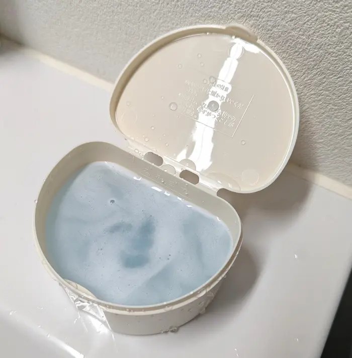 入れ歯洗浄ケースにマウスピースを入れ歯洗浄剤で洗っている様子